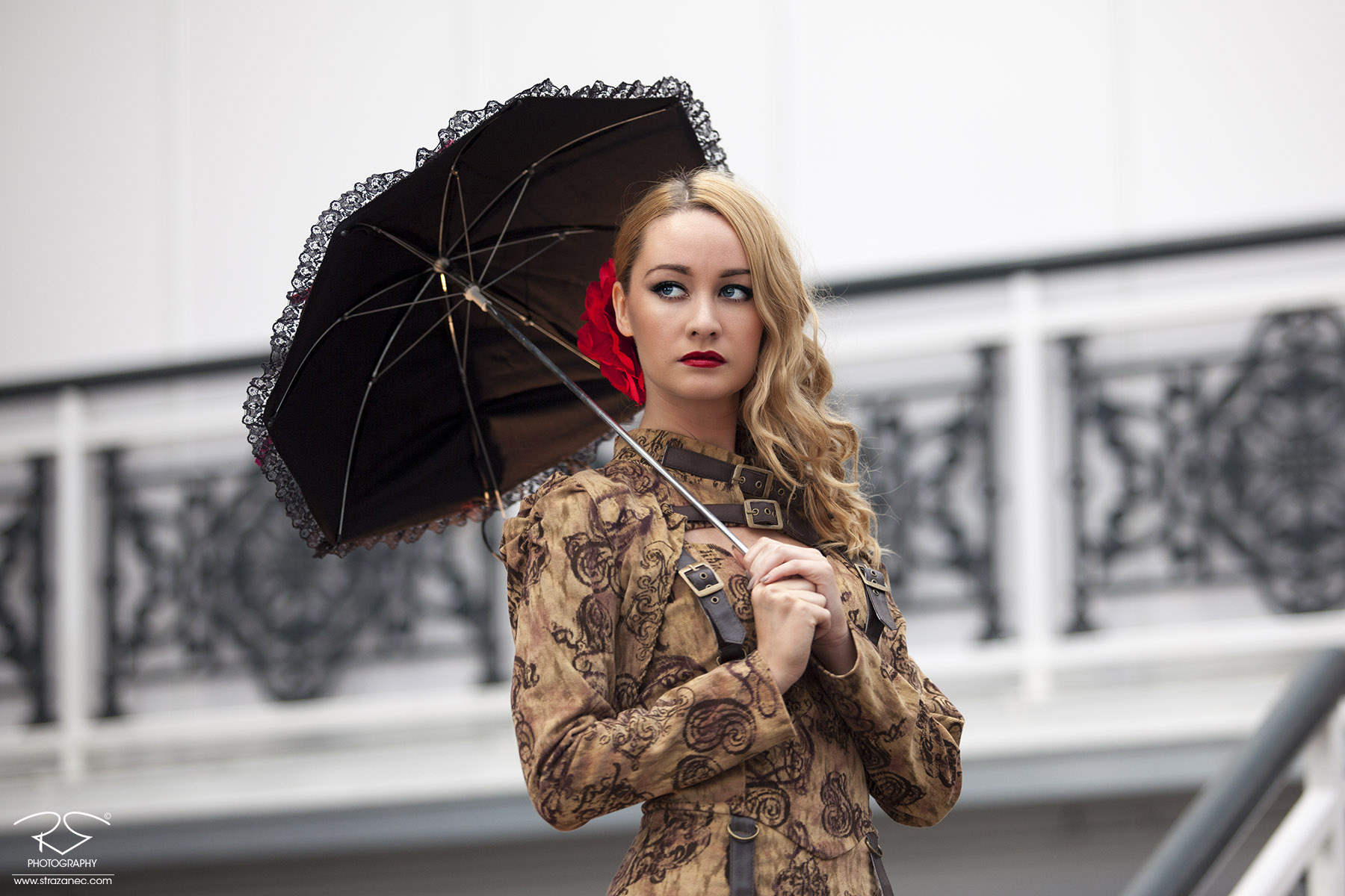 Beautiful blonde girl in steampunk dress with umbrella and red flower in hair.